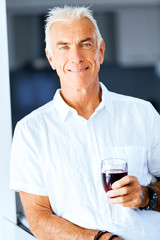 Senior man with holding a glass of wine indoors