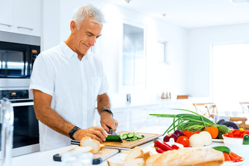 Portrait of a smart senior man standing in kitchen