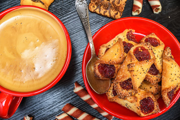 fresh aromatic coffee in a red mug and delicious pastry on a black wooden background
