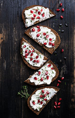 Open sandwiches rye bread with cream cheese and pomegranate seeds, flakes of almond  on marble surface. Healthy snack concept. Top view.