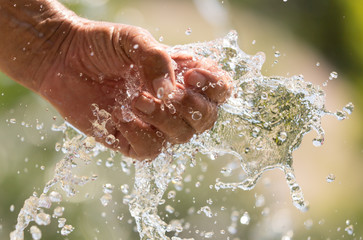 Fototapeta premium Hand of a man in a spray of water from a fountain