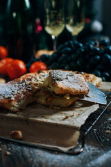 a festive New Year's table, cheese cake with chocolate, tangerines, grapes, biscuits, champagne and two glasses against the backdrop of a decorated Christmas tree with lights