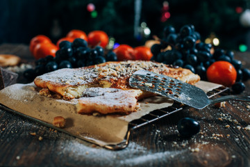 Fototapeta na wymiar cheese cake with chocolate, biscuits, tangerines, grapes on a wooden table