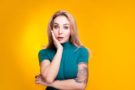 Surprised blonde woman in studio on yellow background