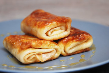 Obraz na płótnie Canvas Bakery. Traditional Russian Pancakes. International Pancake Day on 28 February. Roled delicious pancakes with cheese with honey on gray plate