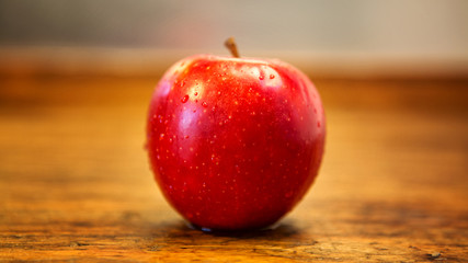red wet apple on rustic wooden table