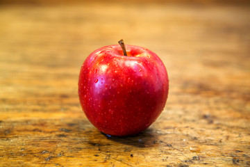 red wet apple on rustic wooden table