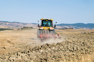 Fototapeta premium Peasant on the tractor while preparing the field for sowing
