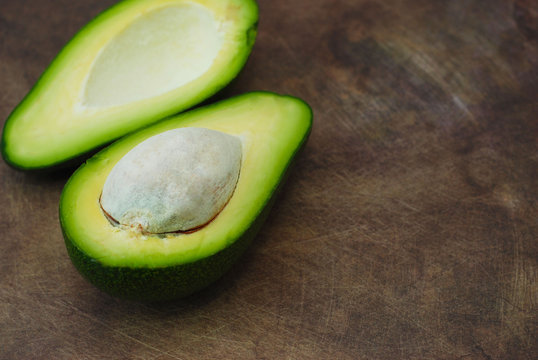 Fresh Avocado sliced over vintage wooden background close up. Ripe green avocado fruit on wood board.