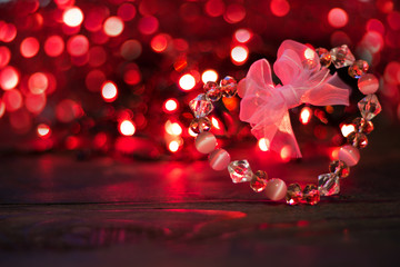 Valentine's day background.Crystal Heart with bow on background of red bokeh lights