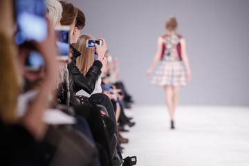 Woman taking picture of new model on fashion show - obrazy, fototapety, plakaty