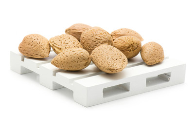 Unshelled almonds on a pallet isolated on white background.