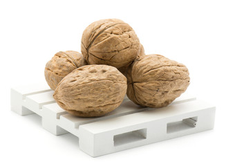 Unshelled walnuts on a pallet isolated on white background.