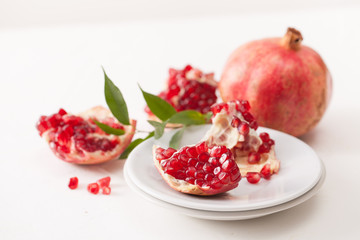 The broken pomegranate fruit with leaves on white