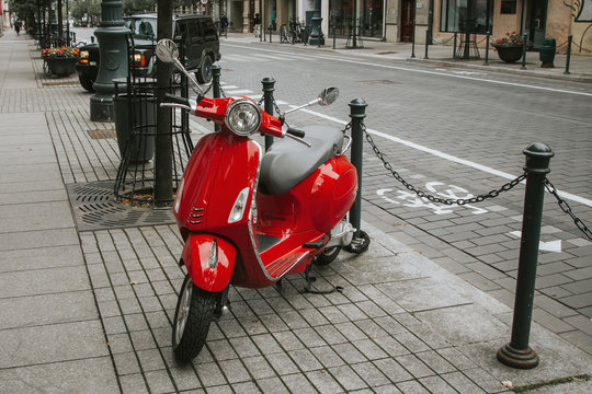 Red scooter parked on the pavement. Europe street photo background.