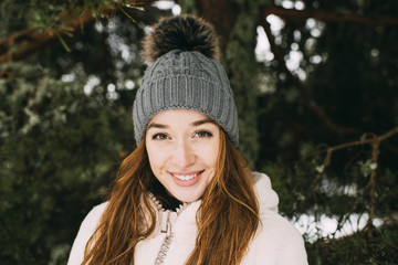 Young beautiful woman wearing stylish coat and glowing garland in nice posing at camera in trees.