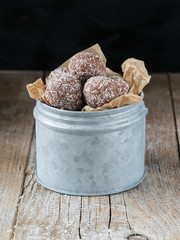 Homemade coconut and chocolate balls in baking paper and metal dose.