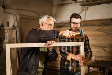 Young and senior carpenter standing in front of a camera