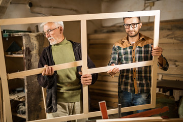 Young and senior carpenter posing in front of a camera