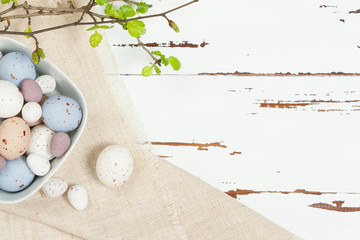 Chocolate Easter Eggs. Natural Linen Textile. Green Spring Leaves. White Wooden Scratched Background.