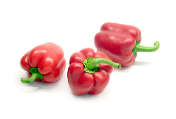 Still life with three whole red ripe bell peppers isolated on white background close up