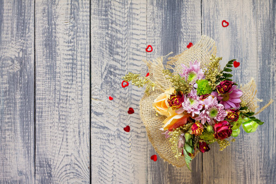 Background Valentine's Day or wedding. Basket bouquet of roses and chrysanthemums on a vintage wooden background. Flat lay. Top view with copy space.