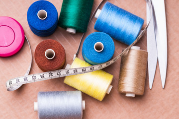 Pile of colorful spools of threa, scissors and measuring meter 