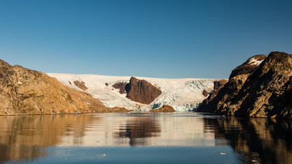 Fototapeta na wymiar Glacier Wrapping Around Rocky Outcropping in Prince Christian Sound Greenland