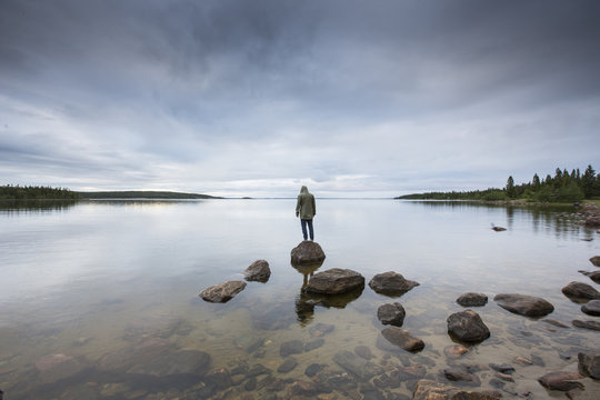 Man standing on rock by a lake in Vasterbotten, Sweden