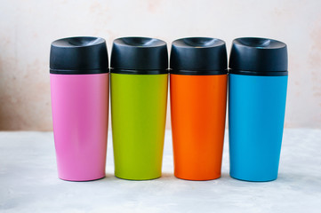 Four plastic thermos mugs on grey background