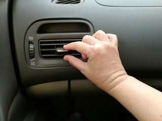 Close-up of hand adjusting air vents to change wind direction inside a car; middle-age hand (Asian skin); Demonstrate the easy or hard adjusting in concepts of too cool or too warm air condition.