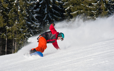 Male snowboarder riding on the snowy slope on beautiful sunny day. Freeride snowboarding copyspace...