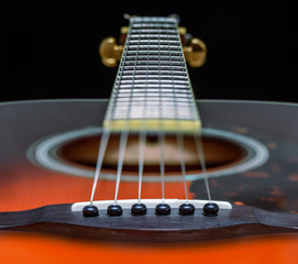 Fototapeta premium Acoustic orange guitar with strings close-up