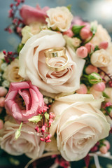 Golden wedding rings on a bridal bouquet with pink roses
