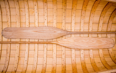 Symmetrical wooden background photo of two paddles lying in a canoe