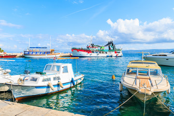 Fototapeta na wymiar Bol port with fishing boats and passenger ferry to Hvar island in background, Brac island, Croatia