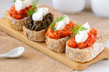 Appetizer bruschetta with mozzarella cheese, pepper-tomato paste, dried tomato paste with garlic and basil and  black olives paste with marinated capers.