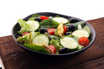 bowl of salad with vegetables and greens, with tomato, cucumber and onions.