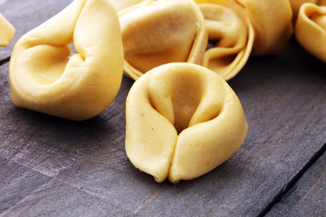 Raw cheese filled tortellini pasta on wooden background