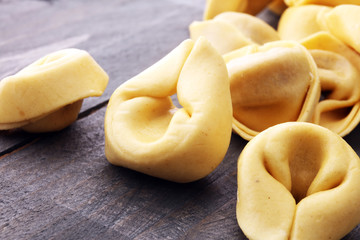 Raw cheese filled tortellini pasta on wooden background