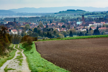 Overlook of the small sixteenth century German town of Einbeck nestled between the rolling hills from a farm road.