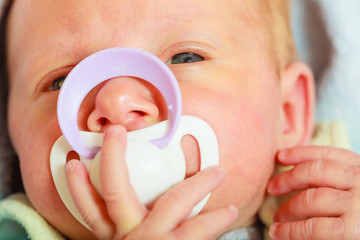 Closeup of little newborn lying with teat in mouth