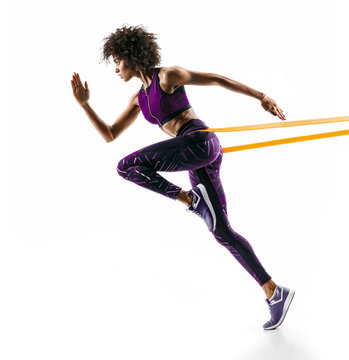 Strong girl in silhouette using a resistance band. Photo of young african girl performs fitness exercises isolated on white background. Side view