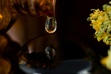 Medical Oil Drop of Cannabis - brown apothecary jar with oil drop and marijuana flower on the brown background.