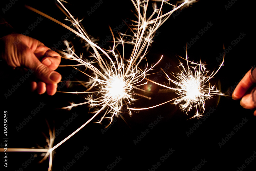 Wall mural sparklers christmas new year's eve celebration darkness two hands