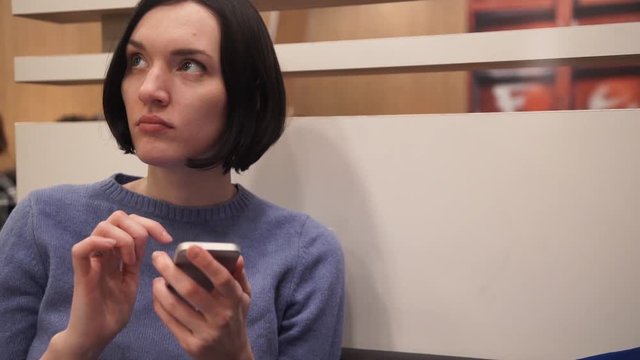 Young attractive woman using smartphone sitting in cafe.