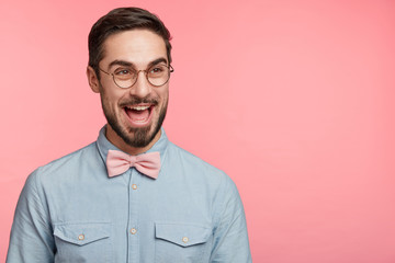Glad handsome young bearded guy has stag party before wedding, looks excitedly aside, spends unforgettable moments with friends, isolated over pink background with copy space for your advertising