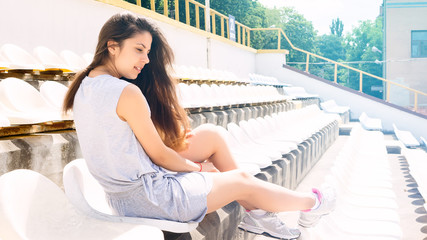 Cute young woman at the stadium in natural clothes of tranquil colors