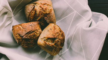 Buckwheat bread bun brioche on a table cloth and black wooden table, moody dark food photography