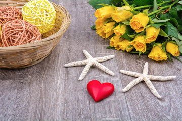 Starfishes, heart and roses on a wooden table